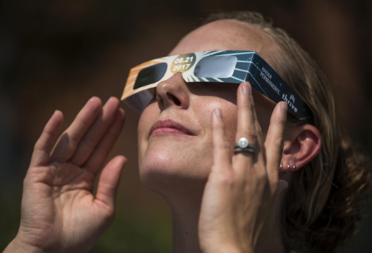 Optometric assistant Rhandy Rogers of Longview tries on a pair of solar eclipse glasses Wednesday outside of the Kaiser Permanente Orchards Medical Office in Vancouver. The eclipse glasses need to be worn to protect the eyes from damage caused by the ultraviolet rays of the sun.