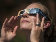 Optometric assistant Rhandy Rogers of Longview tries on a pair of solar eclipse glasses Wednesday outside of the Kaiser Permanente Orchards Medical Office in Vancouver. The eclipse glasses need to be worn to protect the eyes from damage caused by the ultraviolet rays of the sun.