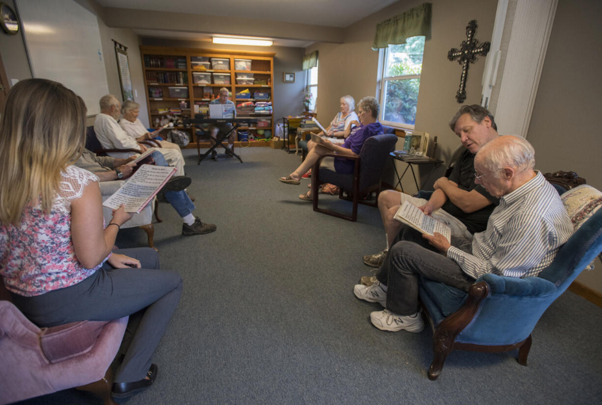 Larry Coatney, a member of Grace Lutheran Church, second from right, shares a song book with memory care client Jerry Knepper, right, while singing traditional Christian hymns at Graceful Living Activity Center on Thursday afternoon.