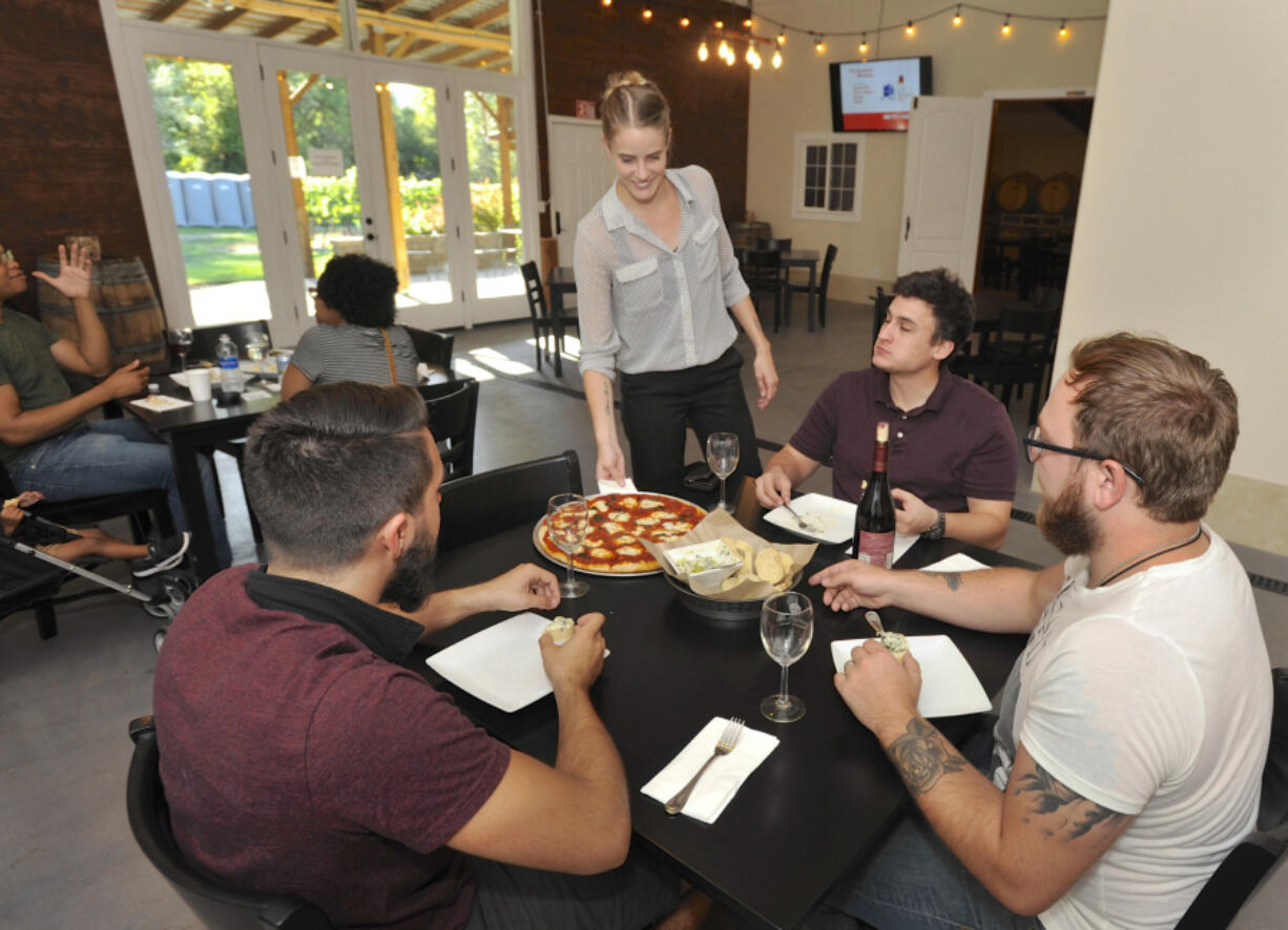 Rachel Hanson serves a pizza to from left, Sean Michel-White, Aron Schwartz and Ed Hanson at Three Brothers Winery in Ridgefield. The winery went from selling prepackaged food to offering its own menu this year.