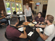 Rachel Hanson serves a pizza to from left, Sean Michel-White, Aron Schwartz and Ed Hanson at Three Brothers Winery in Ridgefield. The winery went from selling prepackaged food to offering its own menu this year.