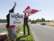 Andy Bao/The Columbian Academic Coordinator Mary Stender, left, and IT systems specialist Aaron Thorne welcome new and returning students to the first day of fall semester at Washington State University Vancouver on Monday afternoon, waving the Cougar flag to passing motorists.