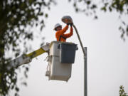 Journeyman lineman apprentice Vince Sorge replaces a high-pressure sodium light fixture with a new LED light fixture in Felida on Tuesday morning. Clark Public Utilities is funding the replacement of 23,000 old light fixtures with the new and more efficient technology.