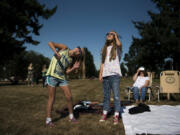 Kayden Williams, 9, left, and her sister Kendall, 11, both of Camas, follow the solar eclipse as it passes through the darkest point Monday morning at Fort Vancouver National Historic Site. “It looked like the Cheshire Cat, but without the eyes,” Kayden said.