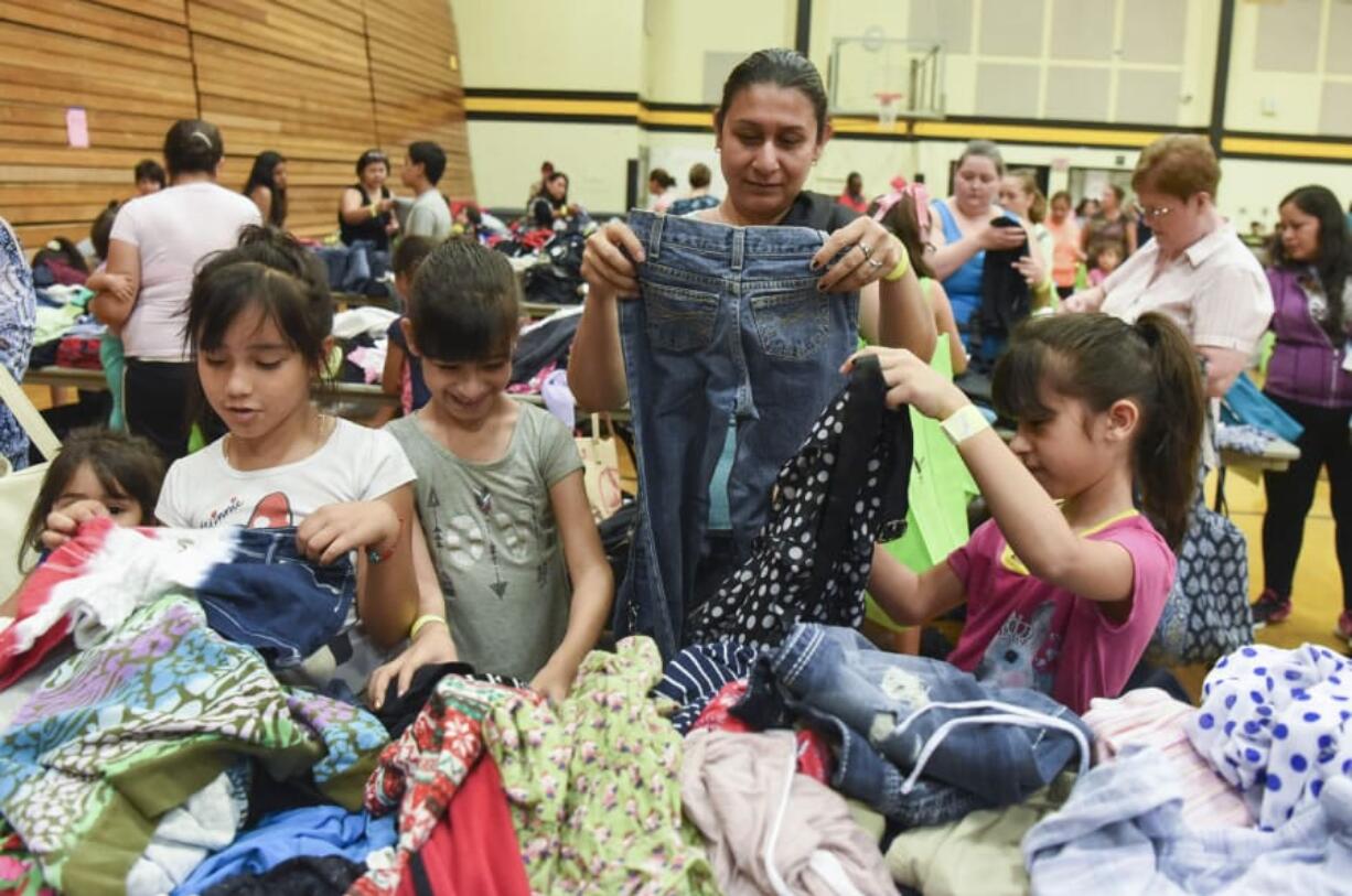 Jahayra Hernandez, 6, from left, Perla Cerrillos, 8, Marcela Anzar, and Paola Cerrillos, 8, sort through free clothing items at the Go Ready! Back-to-School-Readiness Festival at Hudson’s Bay High School in Vancouver.