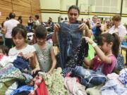 Jahayra Hernandez, 6, from left, Perla Cerrillos, 8, Marcela Anzar, and Paola Cerrillos, 8, sort through free clothing items at the Go Ready! Back-to-School-Readiness Festival at Hudson’s Bay High School in Vancouver.