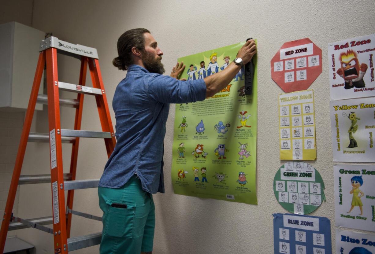 Kyle Sharpe of Vancouver sets up a poster outlining his class’s social curriculum in his new classroom at Chinook Elementary School in Vancouver. An innovative partnership enabled Sharpe to earn his teaching certificate while working as a paraeducator for Vancouver Public Schools and attending classes at the Vancouver campus of City University.