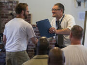 Inmate James Pyles shakes hands with Chaplain Zilvinas Jakstas, right, during the graduation ceremony for the prison’s new program, Language Arts for Healing, at Larch Corrections Center in Yacolt on Thursday. Inmates in the voluntary program spent 16 weeks working with Seattle authors honing their writing skills.