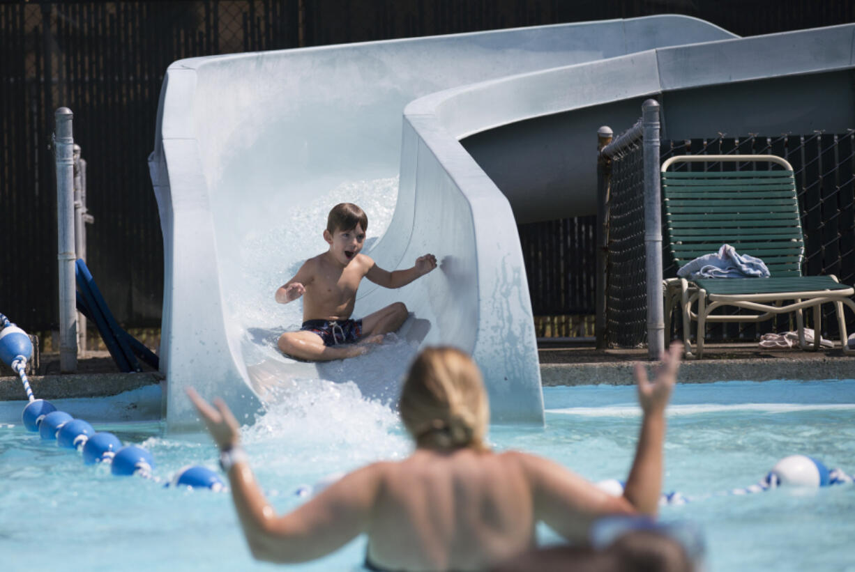 Jaimee Vela reacts as her son Joel, 5, sluices down the waterslide Monday at the Lake Shore Athletic Club in Vancouver. A heat wave is forecast to persist through Labor Day weekend.