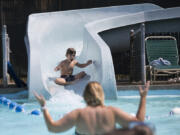 Jaimee Vela reacts as her son Joel, 5, sluices down the waterslide Monday at the Lake Shore Athletic Club in Vancouver. A heat wave is forecast to persist through Labor Day weekend.