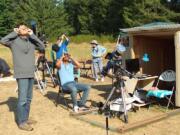 Jacob Sharkansky, standing, from left, Abraham Salazar, seated, and Richard Berry, in background, view the Aug. 21 eclipse while Eleanor Berry looks away from the sun.