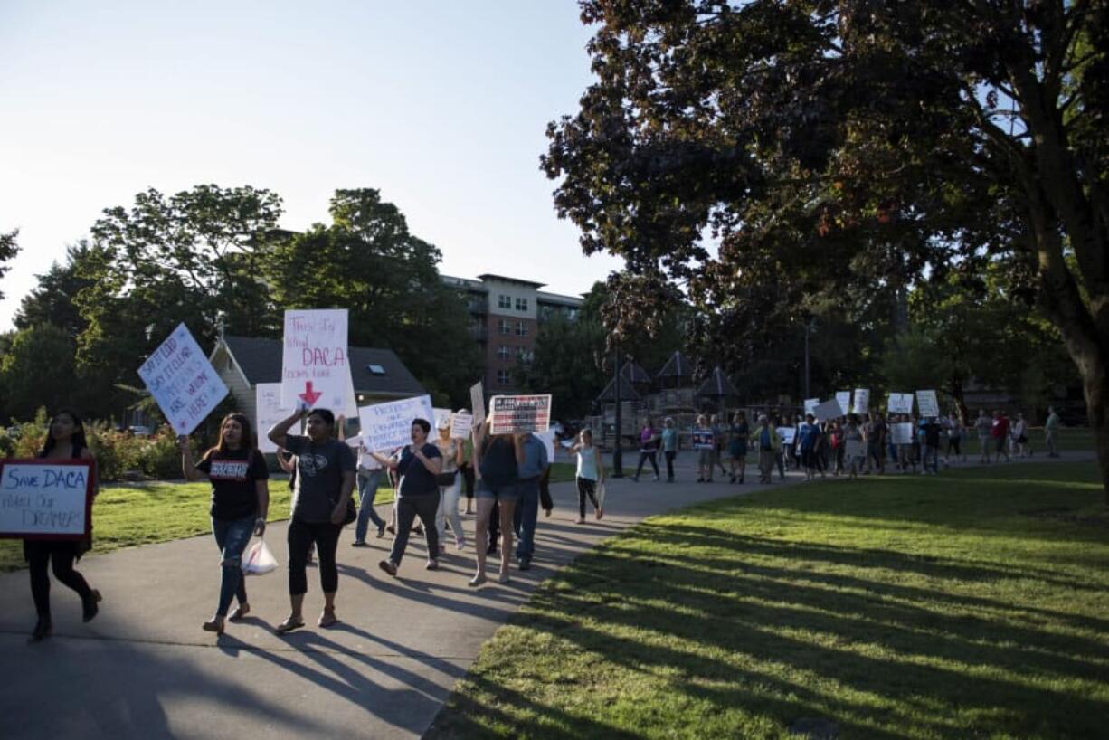 People walk through Esther Short Park during a Save DACA rally hosted by the League of United Latin American Citizens Wednesday evening in downtown Vancouver.