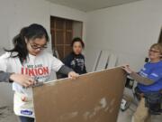 Volunteers for Evergreen Habitat for humanity, from left, Christy Tan, Marianne Gaviola and Terri Brouillet, hang sheetrock in the home of Crystal Helsel at the McKibbin Commons subdivision in Vancouver in May 13.