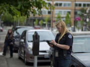 Parking enforcement officer Holly Naramore issues a ticket for an expired meter in downtown Vancouver in May 25.