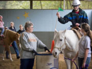 Nancy Elder, center, owner of the Healing Winds Inc., helps lead Tim Smith, 14, through an exercise while on horse back on Saturday November 6, 2009. Elder has been running the center for 20 years, which works mostly with developmentally disabled children. Tim has been visiting the center for 8 years.