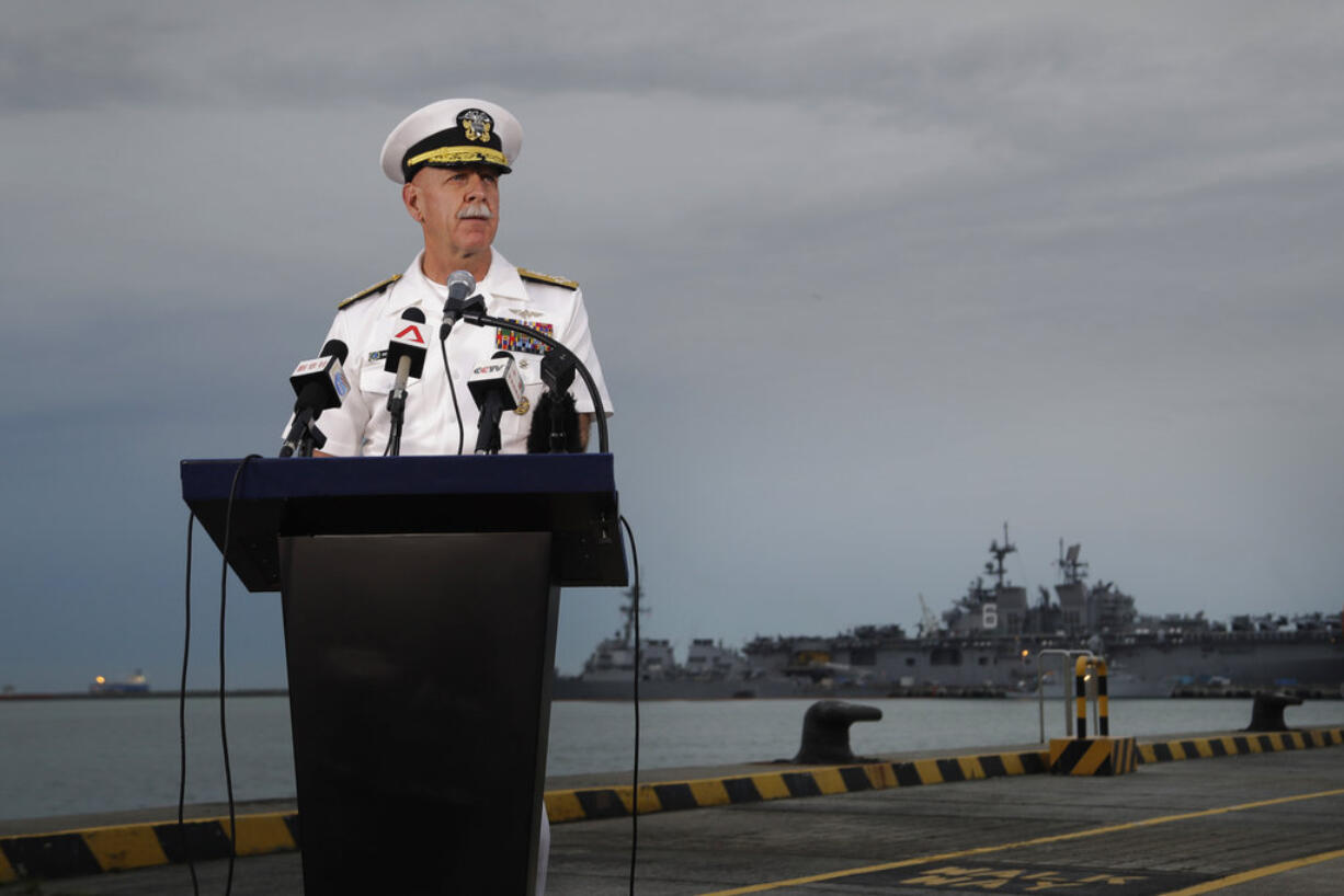 Commander of the U.S. Pacific Fleet, Scott Swift answers questions during a press conference with the USS John S. McCain and USS America docked in the background at Singapore's Changi naval base on Tuesday, Aug. 22, 2017, in Singapore. The focus of the search for 10 U.S. sailors missing after a collision between the USS John S. McCain and an oil tanker in Southeast Asian waters shifted Tuesday to the damaged destroyer's flooded compartments.