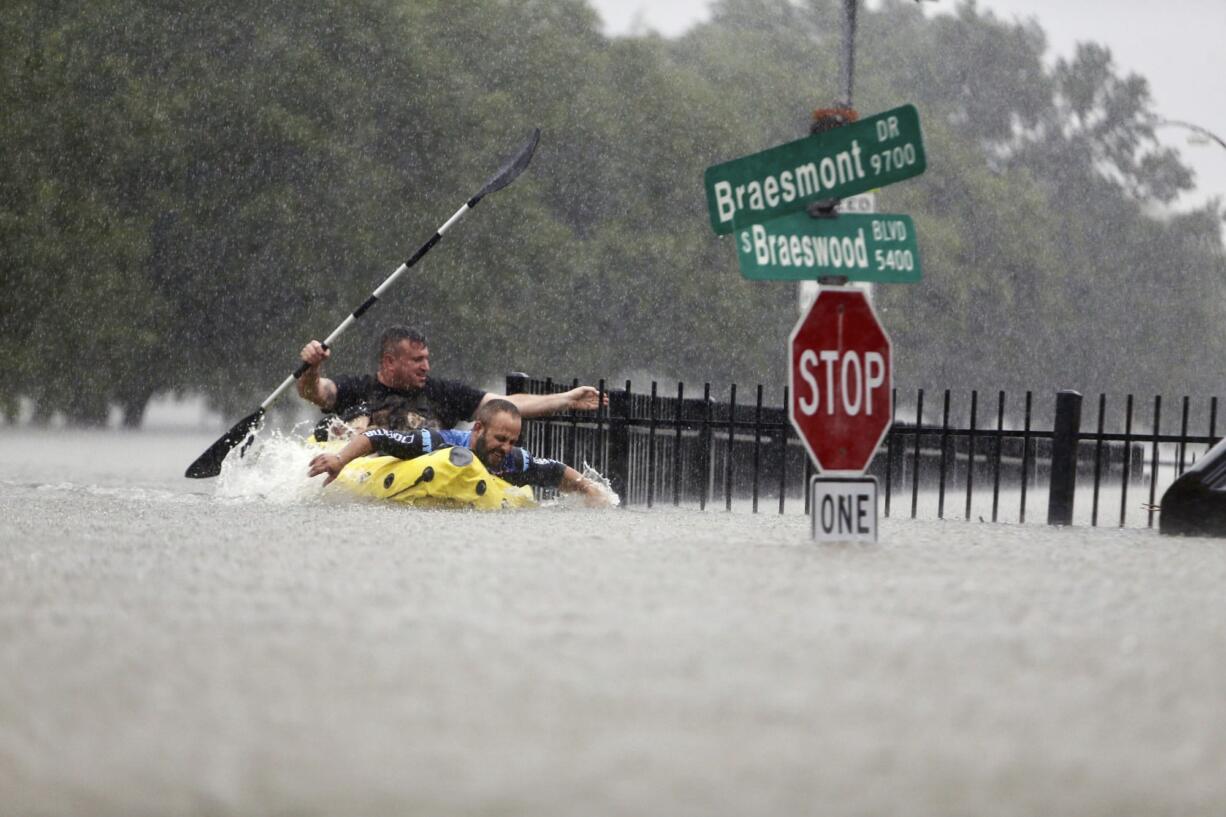 Two kayakers try to beat the current pushing them down an overflowing Brays Bayou from Tropical Storm Harvey in Houston, Texas, Sunday.