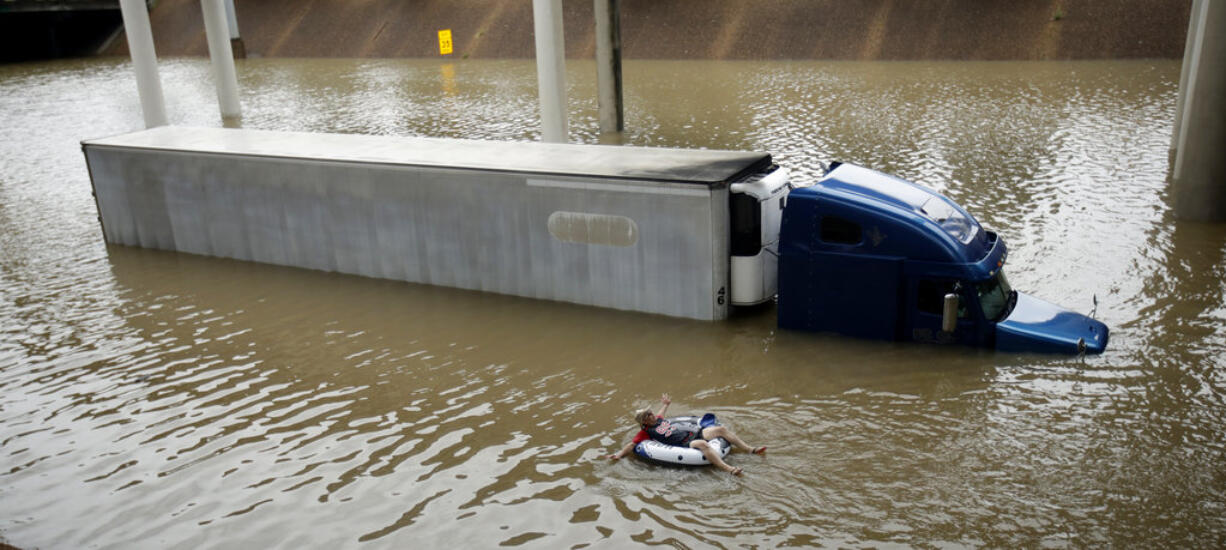 After helping the driver of the submerged truck get to safety, a man floats on the freeway flooded by Tropical Storm Harvey on Sunday, Aug. 27, 2017, near downtown Houston.