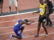 Justin Gatlin, ganador de la medalla de oro, se arrodilla frente a Usain Bolt, ganador del bronce, tras la final de los 100 metros en el Mundial de atletismo, en Londres, el sábado 5 de agosto de 2017.