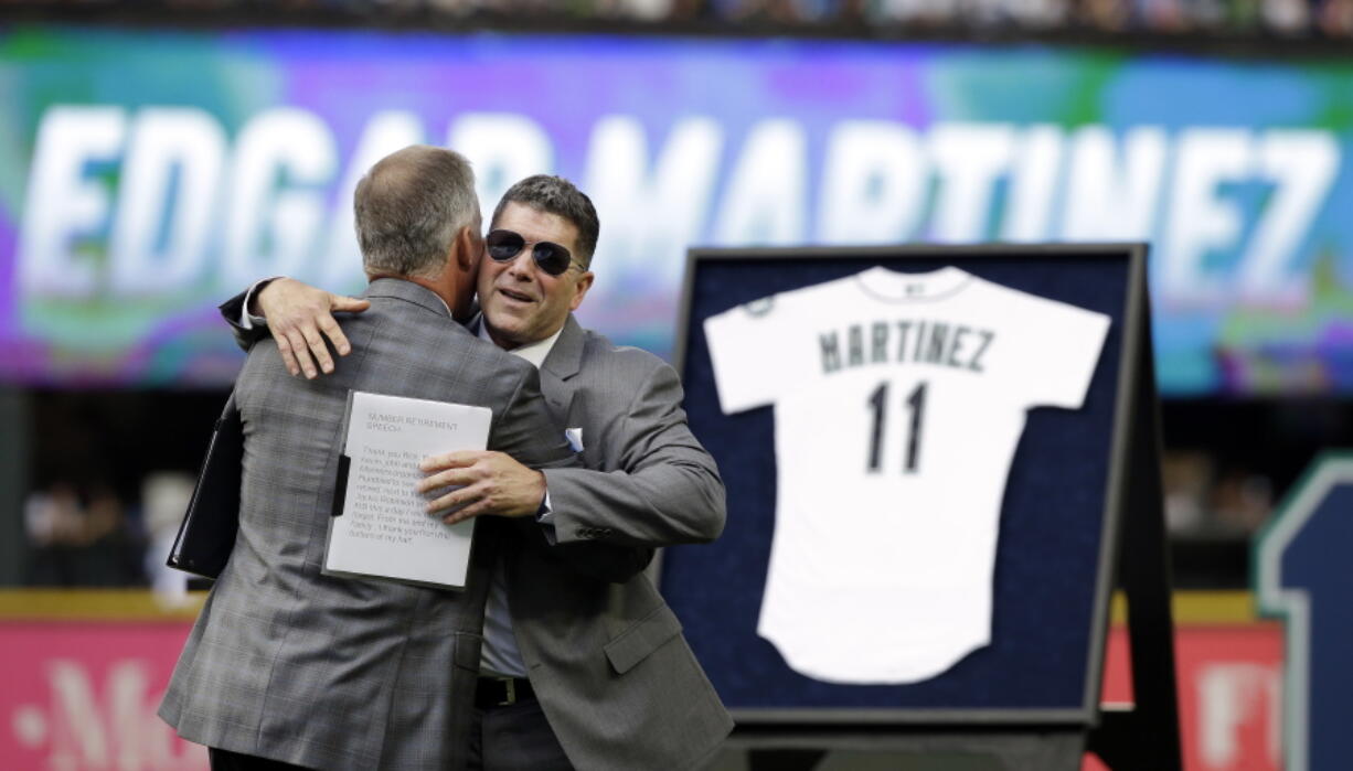 Former designated hitter Edgar Martinez, right, embraces Seattle Mariners president Kevin Mather at a ceremony retiring his No. 11 before a baseball game between the Mariners and the Los Angeles Angels, Saturday, Aug. 12, 2017, in Seattle.