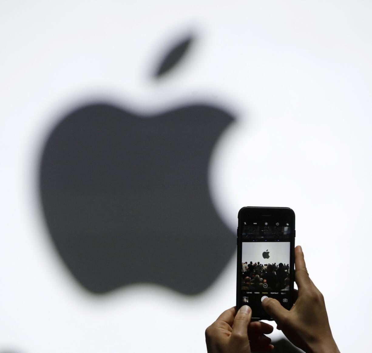 A person takes a photo of an Apple logo.