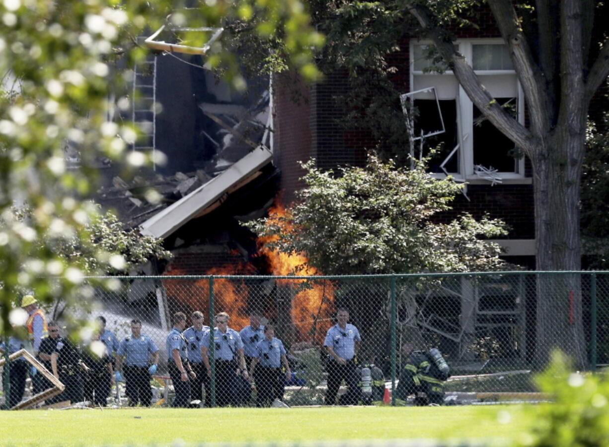 Emergency personnel move away as a gas fire continues to burn following an explosion at Minnehaha Academy on Wednesday in Minneapolis. Several people are unaccounted for after an explosion and partial building collapse Wednesday at a Minneapolis school, fire officials said.