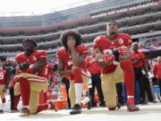 From left, San Francisco 49ers outside linebacker Eli Harold, quarterback Colin Kaepernick, center, and safety Eric Reid kneel during the national anthem before an NFL football game against the Dallas Cowboys in Santa Clara, Calif. What started as a protest against police brutality has mushroomed a year later into a divisive debate over the future of Kaepernick who refused to stand for the national anthem and now faces what his fans see as blackballing for speaking out in a country roiled by racial strife. The once-rising star and Super Bowl quarterback has been unemployed since March, when he opted out of his contract and became a free agent who could sign with any team.