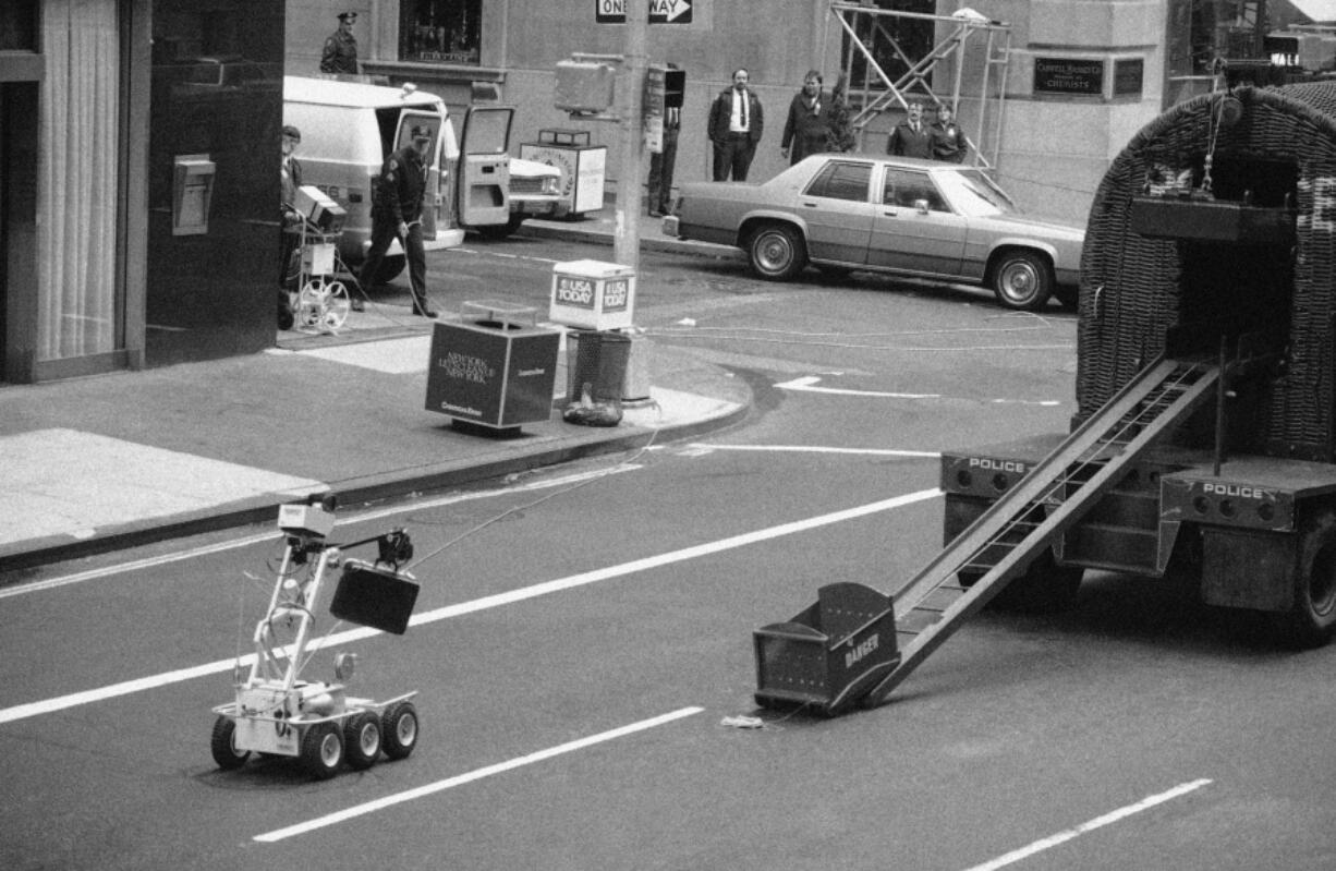 FILE - In this Wednesday, April 20, 1983 file photo, a bomb removal robot, remote controlled by police, at left around the corner, carries a briefcase believed to be a bomb to a waiting truck in New York. It turned out that the suitcase held telephone repairman tools.