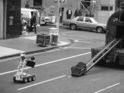 FILE - In this Wednesday, April 20, 1983 file photo, a bomb removal robot, remote controlled by police, at left around the corner, carries a briefcase believed to be a bomb to a waiting truck in New York. It turned out that the suitcase held telephone repairman tools.