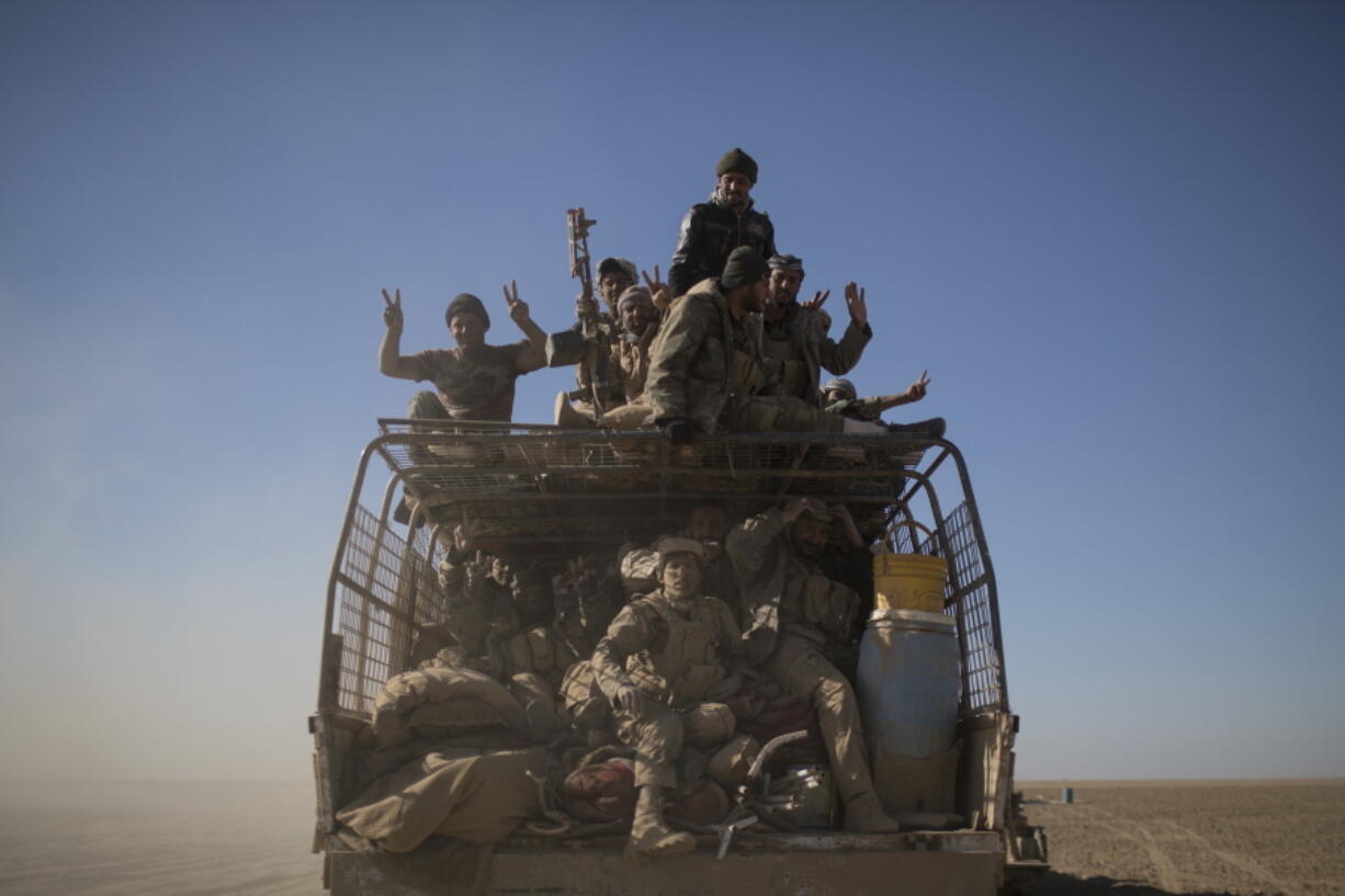 Popular Mobilization Units fighters ride on the back of a truck on their way to fight against Islamic State militants in the airport of Tal Afar, west of Mosul, Iraq, in 2016.