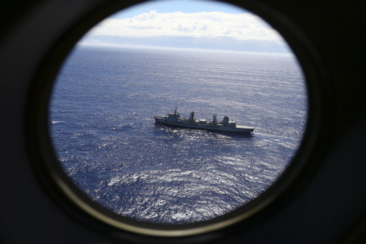 FILE - In this March 31, 2014 file photo, HMAS Success scans the southern Indian Ocean, near the coast of Western Australia, as a Royal New Zealand Air Force P3 Orion flies over, while searching for missing Malaysia Airlines Flight MH370. Scientists have potentially narrowed the search area for the missing Malaysian airliner to three specific locations in the southern Indian Ocean, through new satellite and drift analysis of the 2014 crash released Wednesday, Aug. 16, 2017.