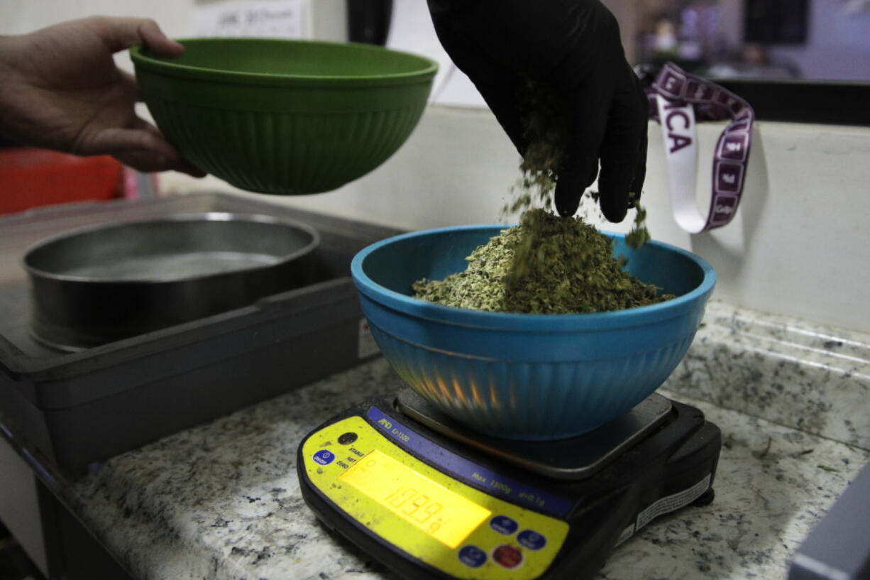 In this June 27, 2017, photo, an employee weighs sifted pot leaves to make joints at the Higher Path medical marijuana dispensary owned by Jerred Kiloh in Los Angeles. On a typical day, $15,000 can change hands in Kiloh’s dispensary, where a steady stream of customers pick from shelves stocked with products, from cannabis-infused lip balm to potent concentrates that look like thin sheets of amber-colored ice. (AP Photo/Jae C.