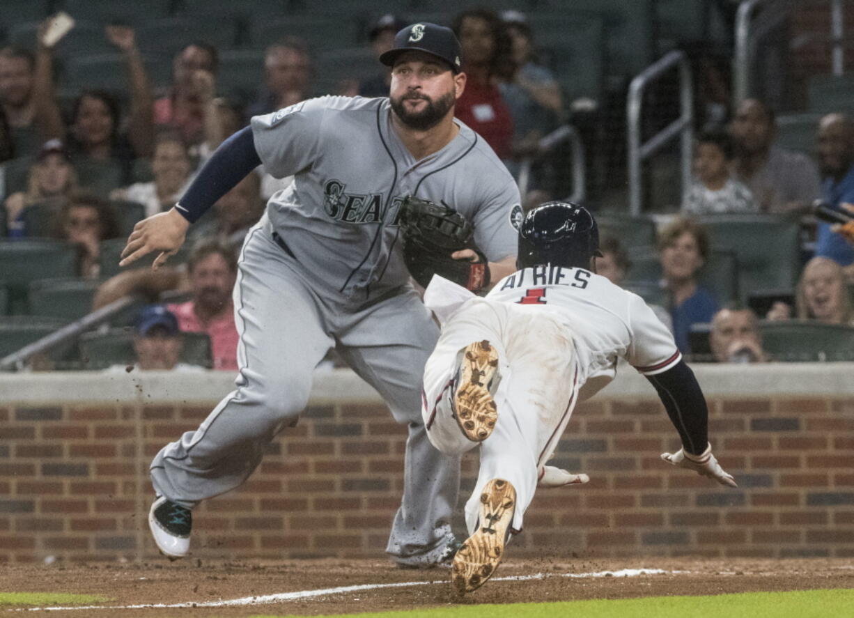 Atlanta Braves second baseman Ozzie Albies dives to home plate to score as Seattle Mariners first baseman Yonder Alonso waits for the throw after a rundown on the third base line during the sixth inning of a baseball game, Tuesday, Aug. 22, 2017, in Atlanta.