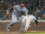 Atlanta Braves second baseman Ozzie Albies dives to home plate to score as Seattle Mariners first baseman Yonder Alonso waits for the throw after a rundown on the third base line during the sixth inning of a baseball game, Tuesday, Aug. 22, 2017, in Atlanta.