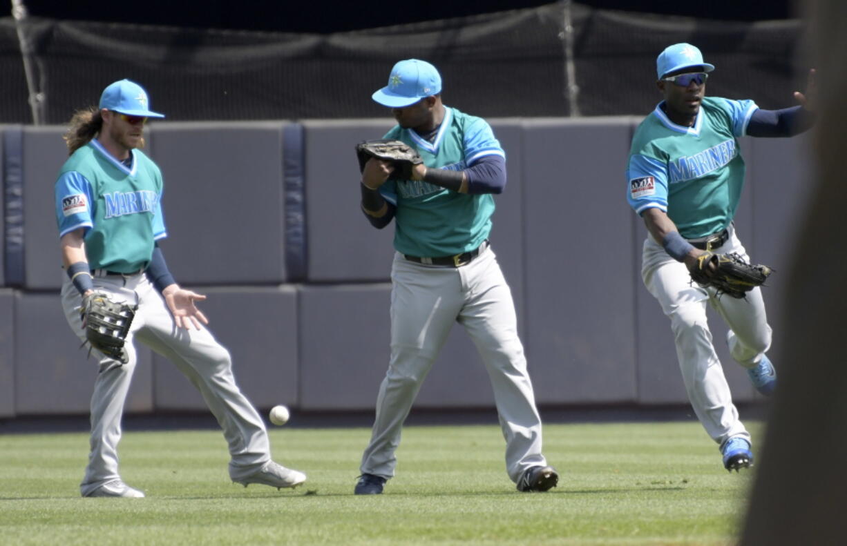 Seattle Mariners left fielder Ben Gamel, left, shortstop Jean Segura and center fielder Guillermo Heredia, right, converge on a single hit by New York Yankees’ Gary Sanchez during the first inning of a baseball game Sunday, Aug. 27, 2017, at Yankee Stadium in New York.