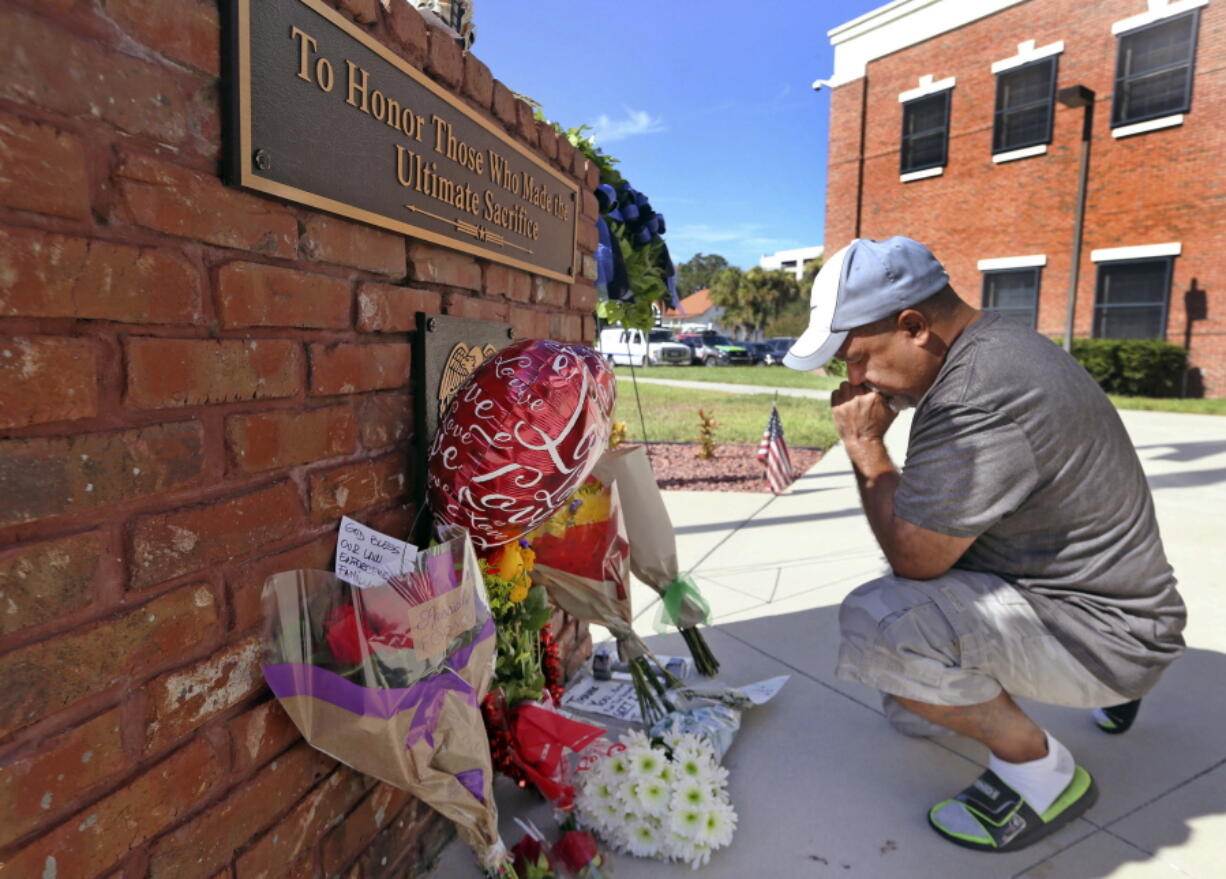 Miguel Velez leaves flowers and says a prayer Saturday at a memorial for the fallen officers in Kissimmee, Fla.