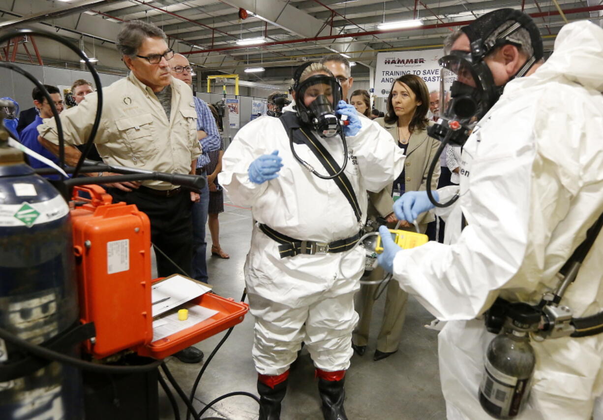 Energy Secretary Rick Perry, left, closely observes as worker trainers Joni Spencer, center, and Dean Beaver prepare to give a respirator demonstration Tuesday at the HAMMER Training Facility in Richland. Rep. Greg Walden, R-Ore., stands next to Perry and Sen. Maria Cantwell, D-Wash., stands in between the workers at right.