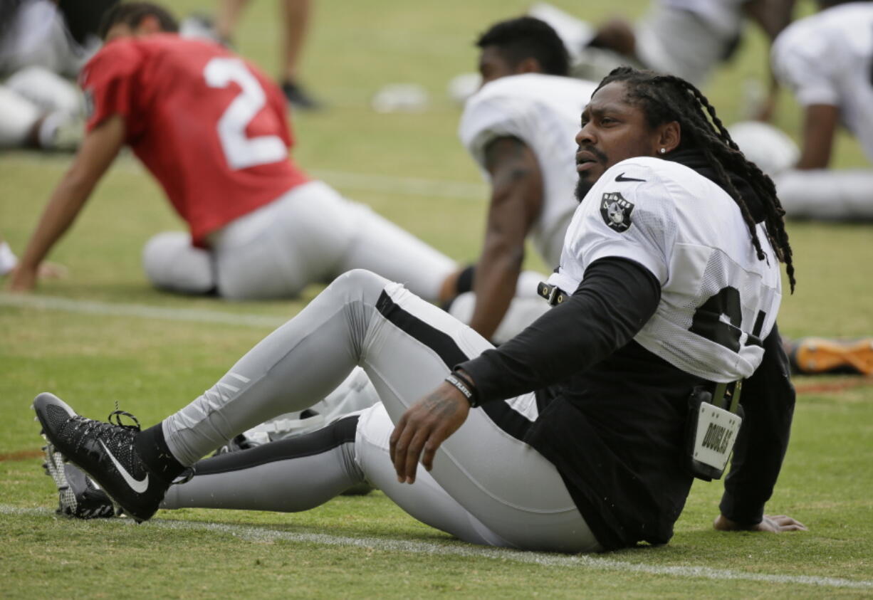 Oakland Raiders running back Marshawn Lynch stretches during an NFL football training camp Friday, Aug. 4, 2017, in Napa, Calif.