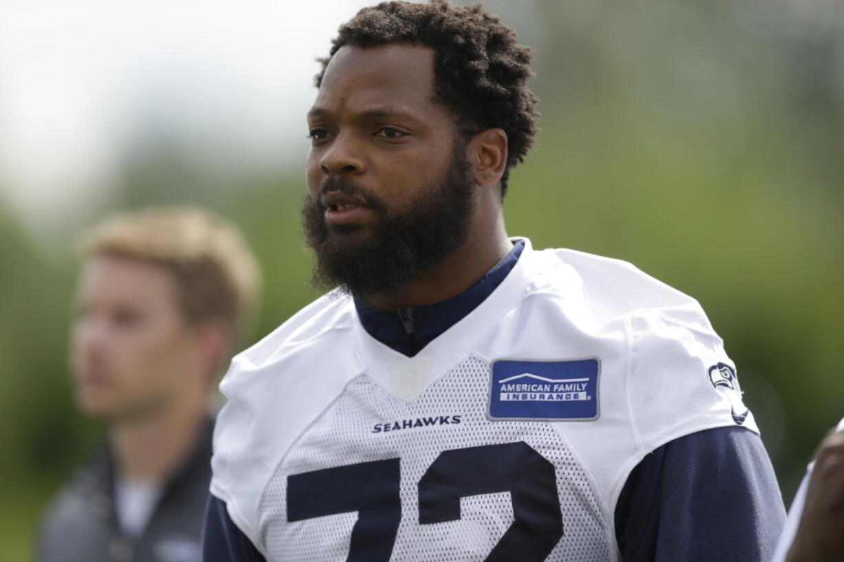 FILE - In this June 13, 2017, file photo, Seattle Seahawks defensive end Michael Bennett walks off the field following NFL football practice in Renton, Wash. Bennett says he will sit during the national anthem this season to protest social injustice and segregation. Bennett sat on the visiting bench during “The Star-Spangled Banner” on Sunday, Aug. 13, 2017, before the Seahawks’ preseason opener against the Los Angeles Chargers, a decision he made prior to protests by white supremacists at the University of Virginia over the weekend. But what happened in Charlottesville, Virginia, including the death of a young woman when she was struck by a car deliberately driven into a group of counter-protesters on Saturday, solidified Bennett’s decision. (AP Photo/Ted S.