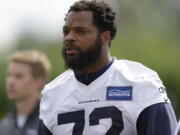 FILE - In this June 13, 2017, file photo, Seattle Seahawks defensive end Michael Bennett walks off the field following NFL football practice in Renton, Wash. Bennett says he will sit during the national anthem this season to protest social injustice and segregation. Bennett sat on the visiting bench during “The Star-Spangled Banner” on Sunday, Aug. 13, 2017, before the Seahawks’ preseason opener against the Los Angeles Chargers, a decision he made prior to protests by white supremacists at the University of Virginia over the weekend. But what happened in Charlottesville, Virginia, including the death of a young woman when she was struck by a car deliberately driven into a group of counter-protesters on Saturday, solidified Bennett’s decision. (AP Photo/Ted S.