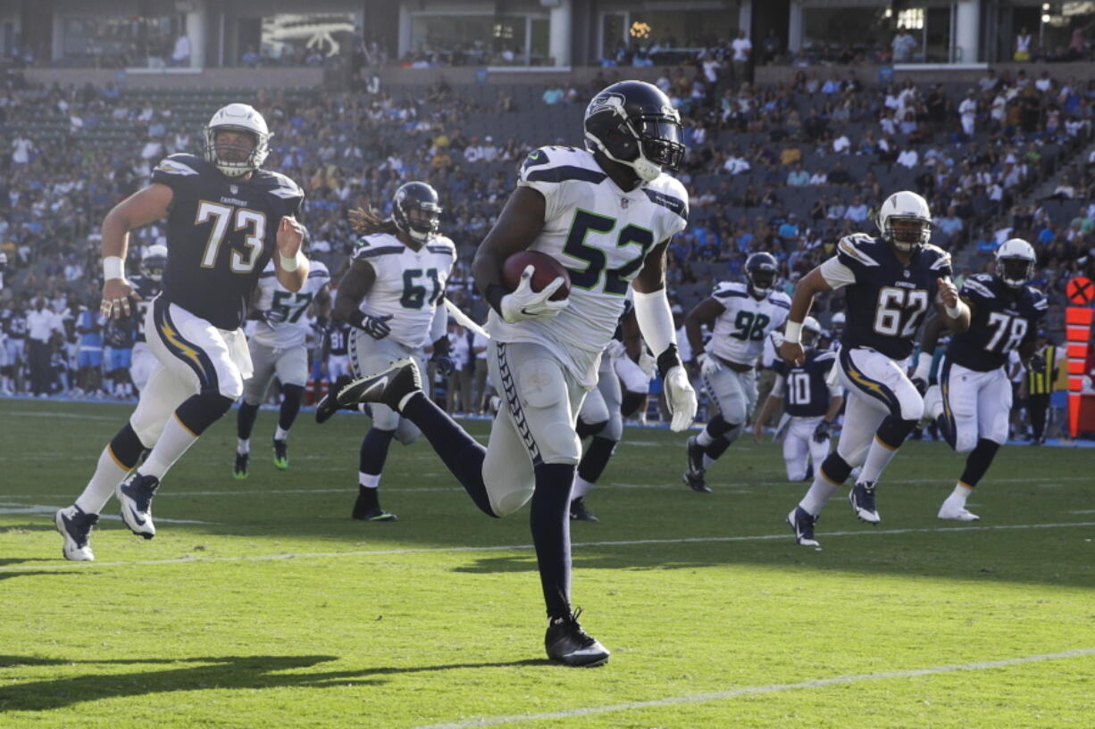 Seattle Seahawks linebacker Terence Garvin (52) runs back an interception for a touchdown against the Los Angeles Chargers Sunday during a preseason game. Garvin is making a strong case to be on the Seahawks’ 53-man roster. Jae C.