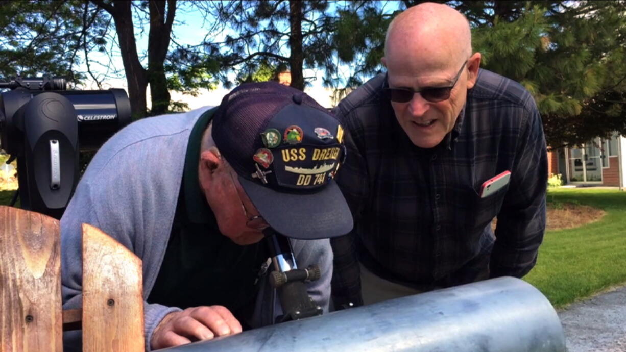 This frame grab from a video shows Gene Brick, 92, left, and his son, Bartt Brick, peer through a telescope in Madras, Ore., on June 12 that they made together in 1964. The two plan to watch the upcoming solar eclipse together August 21 as it passes through Oregon.