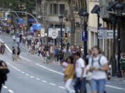 People walk down a main street in Barcelona, Spain, Thursday, Aug. 17, 2017. Police in Barcelona say a white van has mounted a sidewalk, struck several people in the city’s Las Ramblas district.