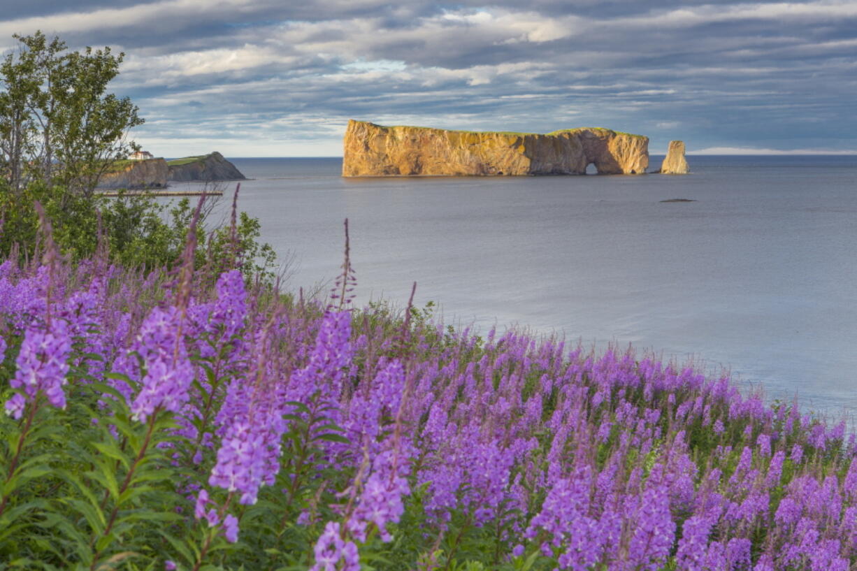 This undated photo provided by Québec Maritime shows Rocher Perce from the Gaspe Peninsula in Québec, Canada. The region offers lighthouses, coastal scenery, whale-watching and attractions like Rocher Perce, a well-known rock formation that rises from the sea with a tunnel-like hole forming an arch beneath it. The loop around the Gaspe is popular with bicyclists and motorcycle riders.