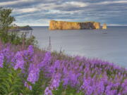 This undated photo provided by Québec Maritime shows Rocher Perce from the Gaspe Peninsula in Québec, Canada. The region offers lighthouses, coastal scenery, whale-watching and attractions like Rocher Perce, a well-known rock formation that rises from the sea with a tunnel-like hole forming an arch beneath it. The loop around the Gaspe is popular with bicyclists and motorcycle riders.