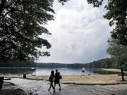 A couple walks along the shore of Walden Pond in Concord, Mass., on July 12. Two centuries after Thoreau’s birth, people are still following in Thoreau’s footsteps to discover Walden Pond, the little lake he immortalized.