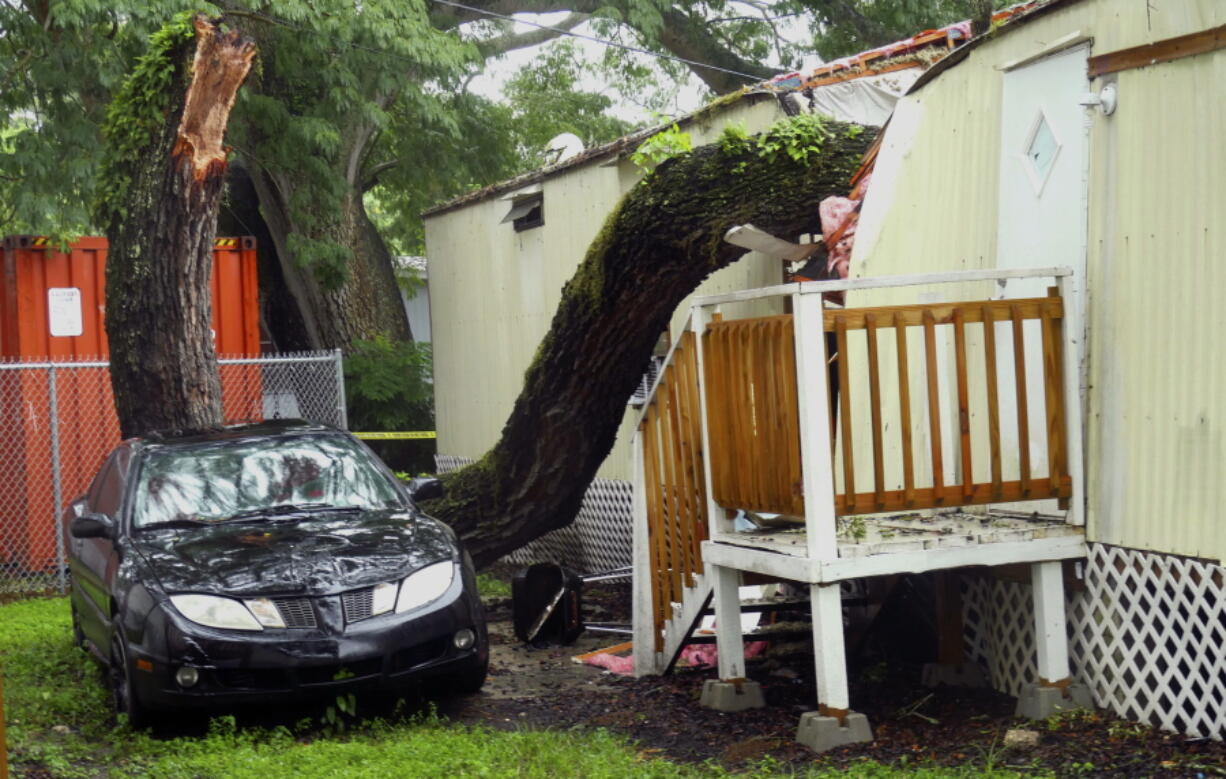 Part of a tree rests on a mobile home in the Easy Living Mobile Home Park after strong winds moved through the area in Tampa, Fla., on Monday.