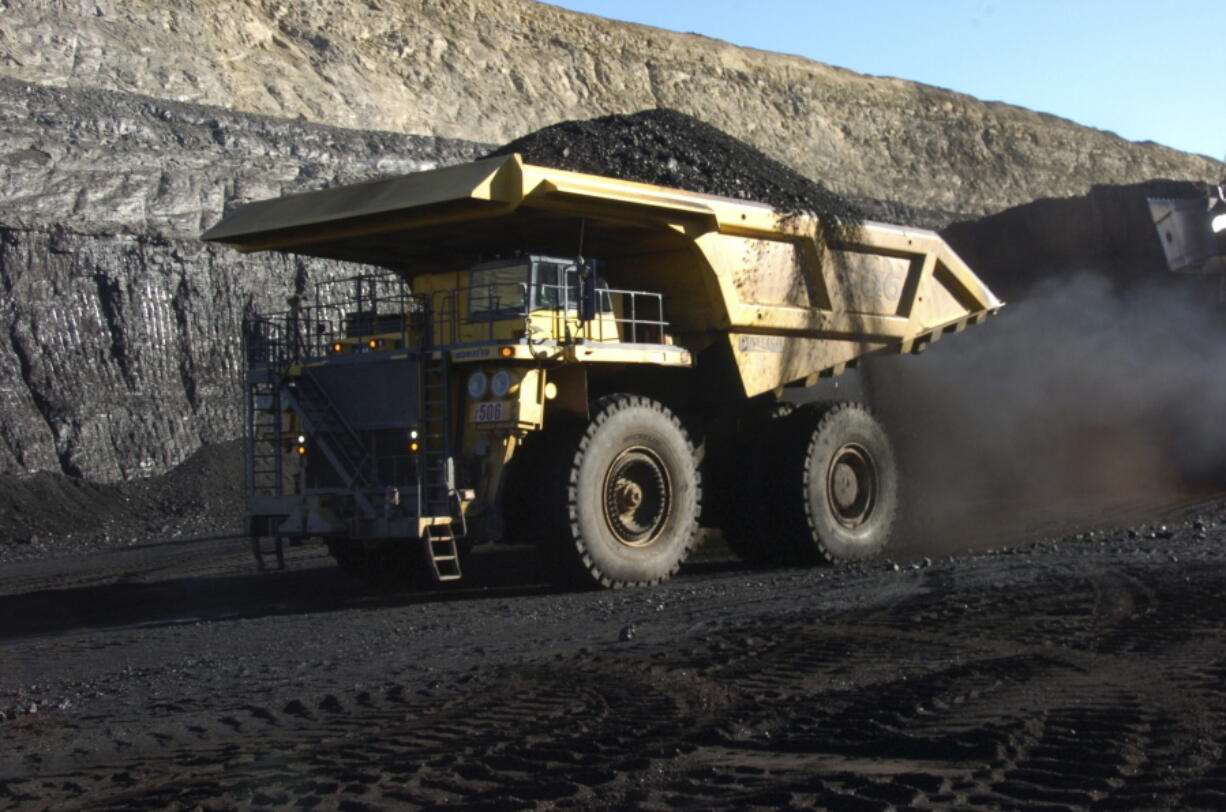 FILE - In this Nov. 15, 2016, file photo, a haul truck with a 250-ton capacity carries coal from the Spring Creek strip mine near Decker, Mont. As President Donald Trump touts new oil pipelines and pledges to revive the nation’s struggling coal mines, federal scientists are warning that burning fossil fuels is already driving a steep increase in the United States of heat waves, droughts and floods.