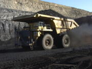 FILE - In this Nov. 15, 2016, file photo, a haul truck with a 250-ton capacity carries coal from the Spring Creek strip mine near Decker, Mont. As President Donald Trump touts new oil pipelines and pledges to revive the nation’s struggling coal mines, federal scientists are warning that burning fossil fuels is already driving a steep increase in the United States of heat waves, droughts and floods.