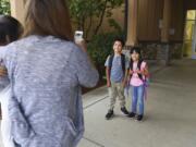 Rosa Garcia, left, takes a photo of her children, Alejandro Ramirez-Garcia, a third-grader at Fruit Valley Elementary School, center, and kindergartener Adamaris Ramirez-Garcia at the entrance of Fruit Valley on the first day of school Wednesday in Vancouver.